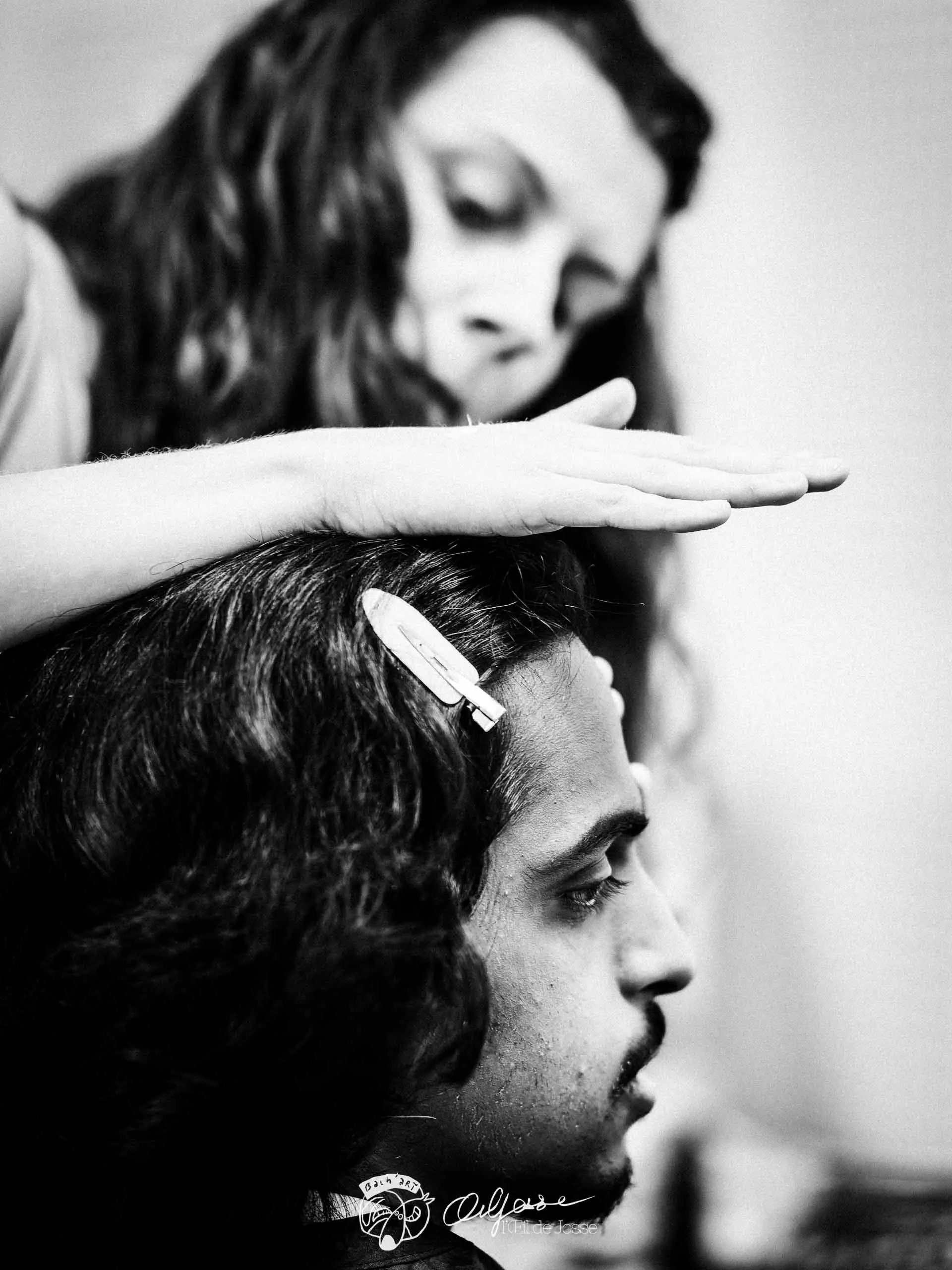 Une maquilleuse prépare la coiffure d’un comédien avant le spectacle.